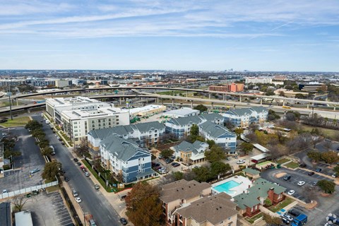 A large apartment complex with a pool in the foreground and a cityscape in the background.